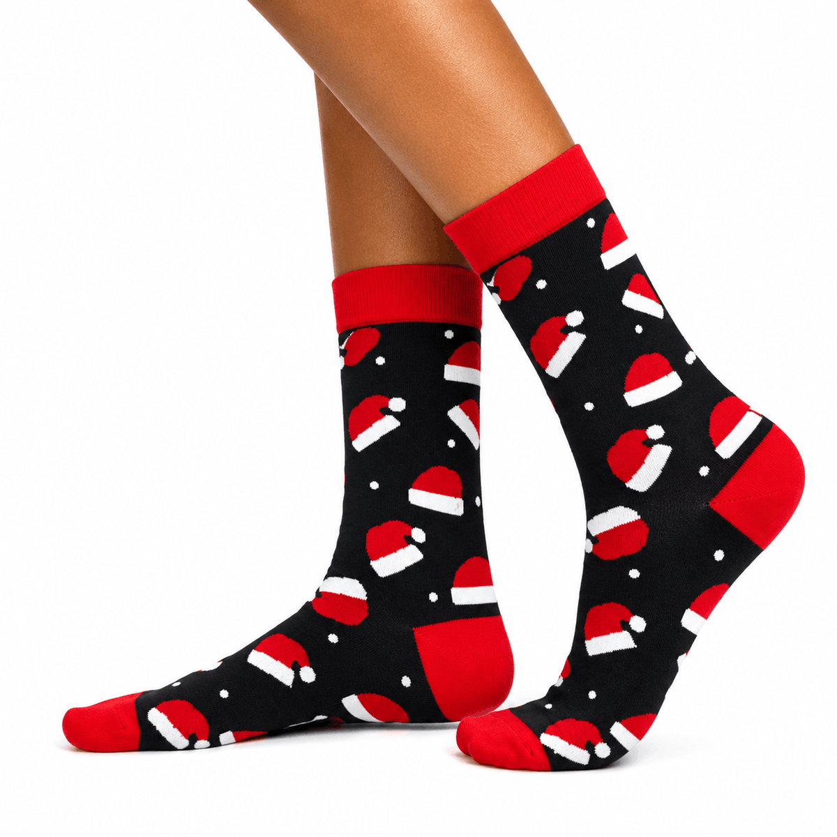 A pair of crew socks with a black background and a red and white Santa hat pattern, shown on a model's feet against a white background.